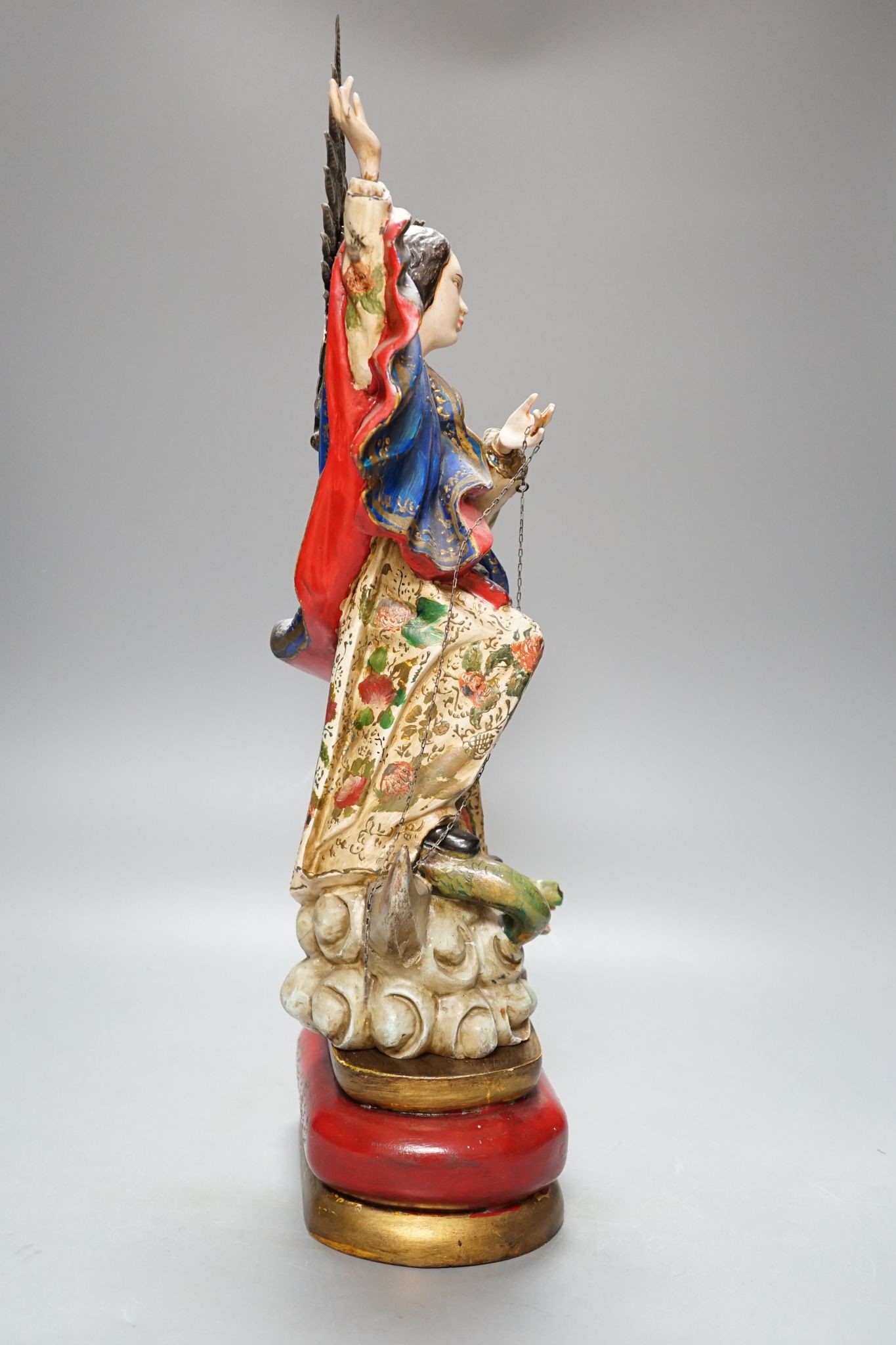 A painted South American angelic figure, standing on a dragon on a crescent moon 49cm